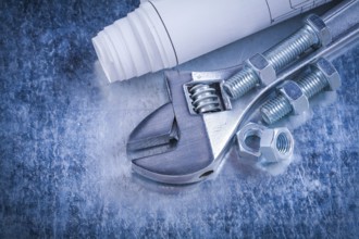 Steel adjustable spanner screw-nuts bolts and blueprints on scratched metallic background