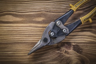 Tin snips on vintage wooden board top view construction concept