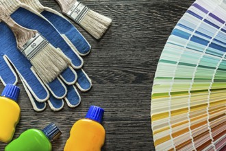 Safety gloves paint brushes bottles pantone fan on wooden board