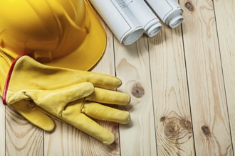 Gloves helmet and construction blueprints on wood
