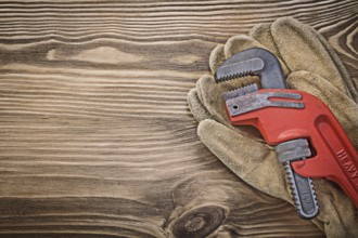 Pair of leather protective gloves monkey wrench on wood board construction concept