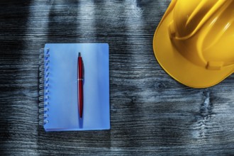 Notepad pen hard hat on wooden board