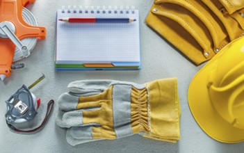 Protective gloves hard hat notepad pencil tool belt measuring tape on concrete background