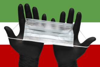 Doctor holds respiratory face mask in hands in black medical gloves on background colors flag of