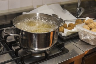 Chef frying food in flaming pan on gas hob in commercial kitchen