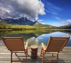 Two comfortable wooden sun beds for tourists, interconnected table. Pyramid Mountain reflected in