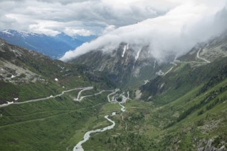 Situation on Furka pass on a cloudy summer day. View into the Rhone valley with mountain passes.