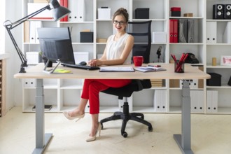 A young girl is sitting at the desk in the office