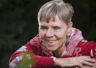 Portrait of an elderly woman on a park bench in summer with her upper body turned backwards over