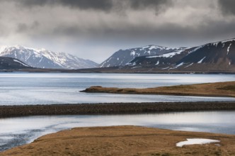 Icelandic dramatic landscape with frozen lake and mountains covered in snow at snaefellsnes