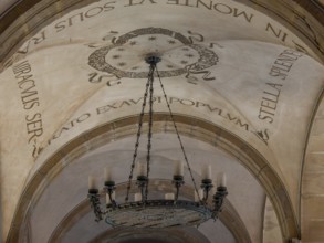 Decorated ceiling with Latin lettering and large chandelier, montserrat, spain