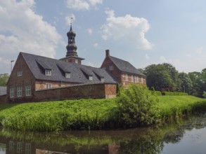 Historic brick building with tower and pond, surrounded by a green garden and blue sky, husum,