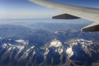 Silver wing and snow, aeroplane flies over the Swiss Alps, Switzerland