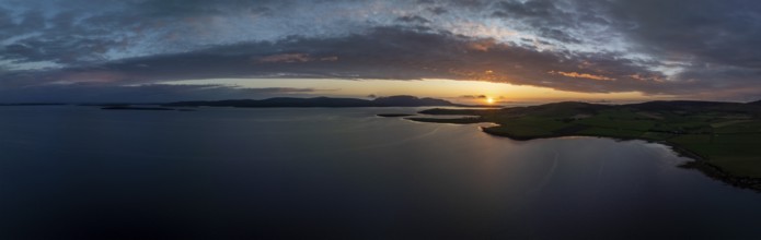 Sunset with cloud band on the coast of Scapa Flow with view to the island of Hoy, drone shot,