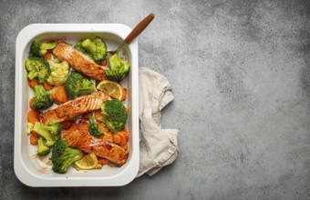 Top view of healthy baked fish salmon steaks, broccoli, cauliflower, carrot in casserole dish on