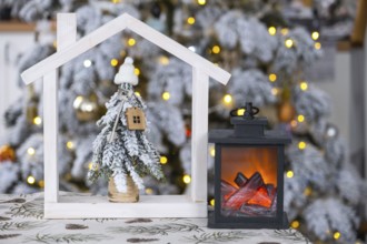 Key on Christmas tree and tiny house on cozy home with Christmas decor on table of festive white