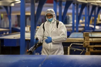 Sofia, Bulgaria - 7 April, 2020: Worker sprays disinfectant outside of ? food market against the