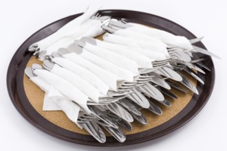 Many forks and knives folded for one person on tray