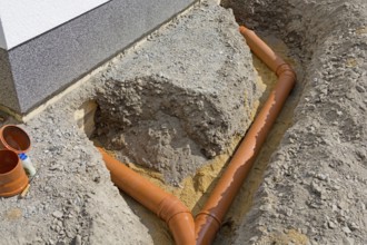 Open trench with laid sewage pipes at residential building