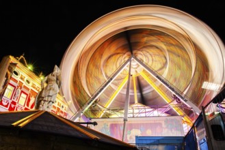 Stone sculpture, miner's fountain in front of Ferris wheel, long exposure, night shot, Leoben,