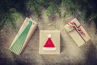 Green pine tree branches handmade gift boxes on burlap background