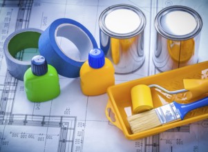 Blueprint with paint brush tray roller cans bottles and household tapes close up image construction