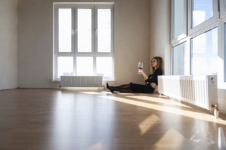 Beautiful elegant girl sits on the floor in a large light room with stained glass windows