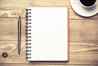 White blank notepad with cup of coffee on wooden table