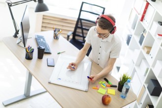 A young man in a white shirt and light jeans is working in a bright office. photo with depth of
