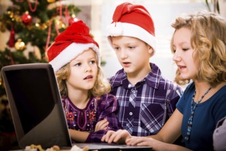 Kids surfing with a laptop at the christmas tree