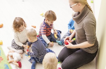 Children with teacher in kindergarten playing cooks