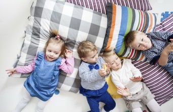 Cute little boys and girls lying on the pillows and playing in the kindergarten, top view