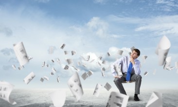 Young businessman sits on an office chair, thoughtful and looking up