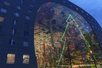 Modern glass façade with large neon-lit Christmas tree decoration at dusk, Rotterdam, Netherlands