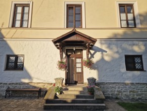 Rustic old building facade with porch and a charming wooden door, framed by two side windows and a