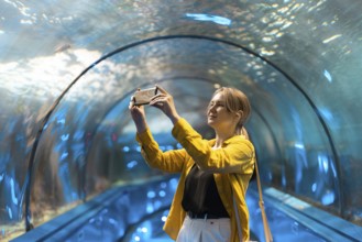 Eine Frau in einem Unterwassertunnel mit Meeresbewohnern