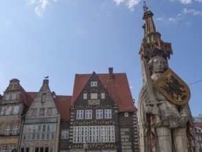 Historic old town with half-timbered houses and a large statue under a blue sky, Bremen, Germany