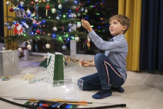Happy boy opening a Christmas gift and Christmas tree in the background