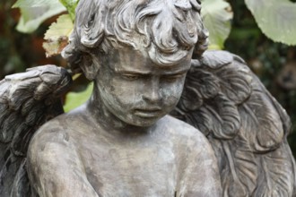Little angel in a cemetery looks sadly to the ground