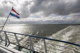 Wadden Sea with Dutch flag and wake as seen from the ferry