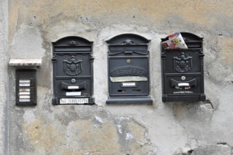 Three worn letterboxes on an old, faded wall, Orvieto, Italy