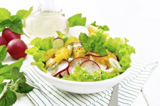 Radish, onion and orange salad with mint, vegetable oil and spices on lettuce in a plate on a towel