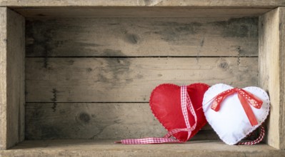 An image of two felt hearts on a wooden background