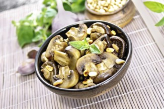 Champignons baked with oregano, wine, garlic, lemon and pine nuts in bowl on background of brown
