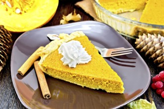 A piece of pumpkin pie with whipped cream in a brown plate with a fork and cinnamon, pumpkin,