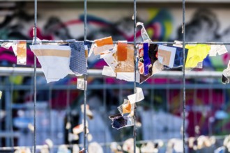 Scraps of paper against a wire fence, symbolising creativity, disorder, protest