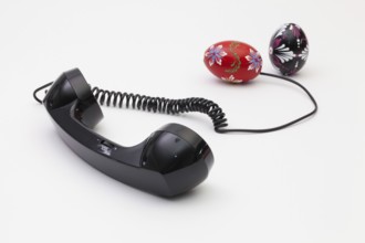 Old phone reciever and cord connection with Easter eggs. Easter hotline concept