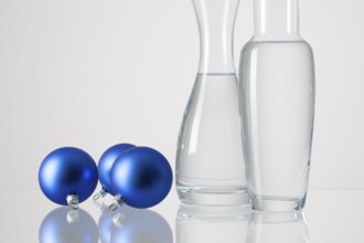 Two vases with clean water and Christmas decoration on a glass table