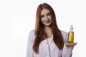 A smiling woman proudly displays a bottle of golden hair oil, promoting effective hair care