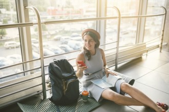 Theme of tourism and travel of young student. Beautiful young caucasian girl in dress and hat sits